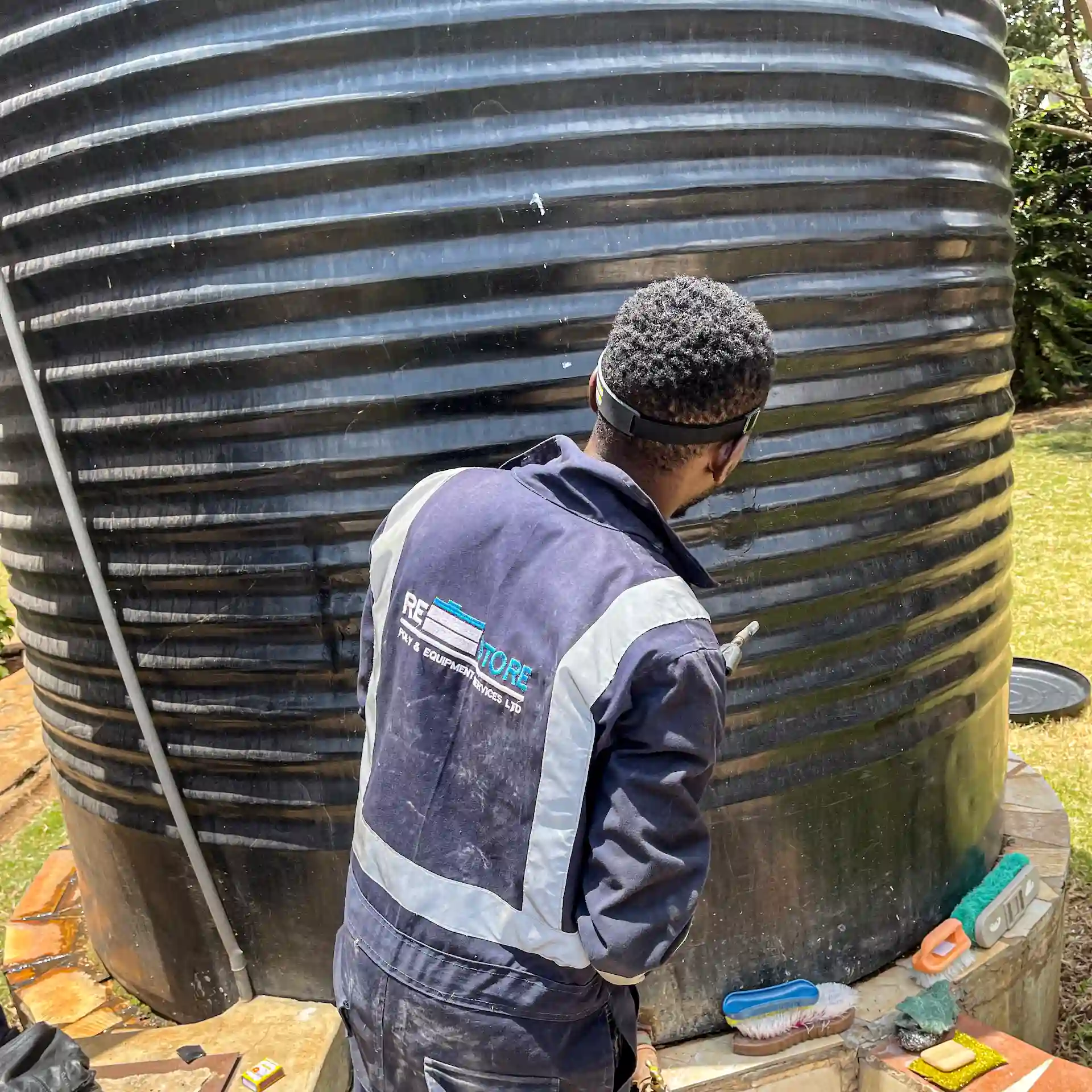 Restore Services technician performing precision plastic welding repair on large industrial black ribbed water tank with professional tools